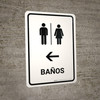 Restrooms With Left Arrow White Spanish Portrait - Wall Sign