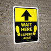 Wait Here with Arrow and Feet Icons Bilingual Spanish Portrait - Wall Sign