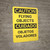 Caution: Flying Objects Bilingual Spanish - Wall Sign
