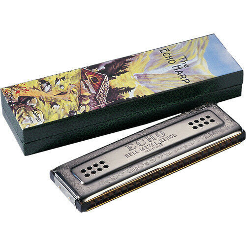 Hohner Tremolo Echo Harp harmonica with a metallic body engraved with 'HOHNER ECHO MADE IN GERMANY,' shown next to its box featuring colorful mountain artwork and 'THE ECHO HARP' text.