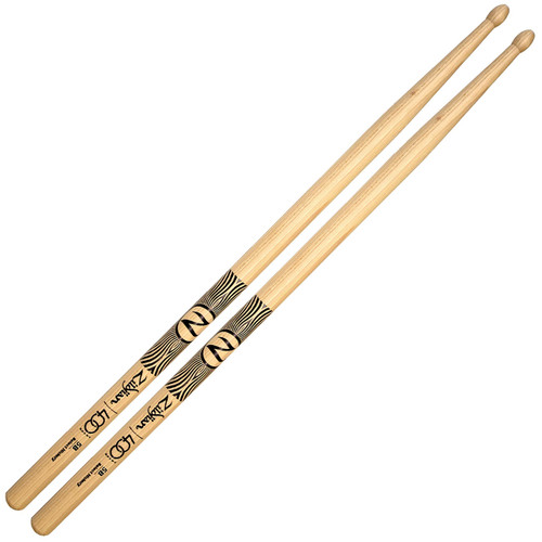 The image shows two wooden drumsticks with the brand name "Zildjian" printed on them. The drumsticks have a natural wood finish and feature black decorative patterns near the middle. The model number "5B" is also printed on the drumsticks
