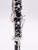 A close-up view of the middle section of a black clarinet, highlighting its silver keys and rings, with no additional elements or text in the background.