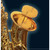 A close-up of a gold baritone saxophone with a Saxmute mute attached to its bell.