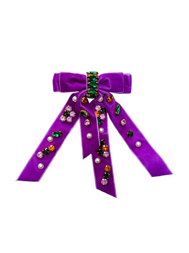Mardi Gras Bejeweled Ribbon Bow. Made from purple velvet ribbon, this bow is adorned with sparkling purple, green, and gold costume jewels, as well as white costume pearls. With a secure metal clip, you can easily attach it to hair. Measures about 4in x 6.75in with tails.