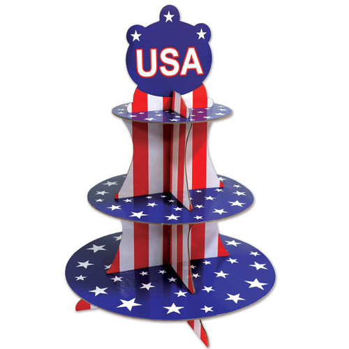 Patriotic Cupcake Stand! Featuring 3 blue tiers with white stars and supports printed in classic red and white stripes. Topping it off is a blue shaped centerpiece decorated with white stars and a "USA" graphic in white with a red outline. Measures 16in.