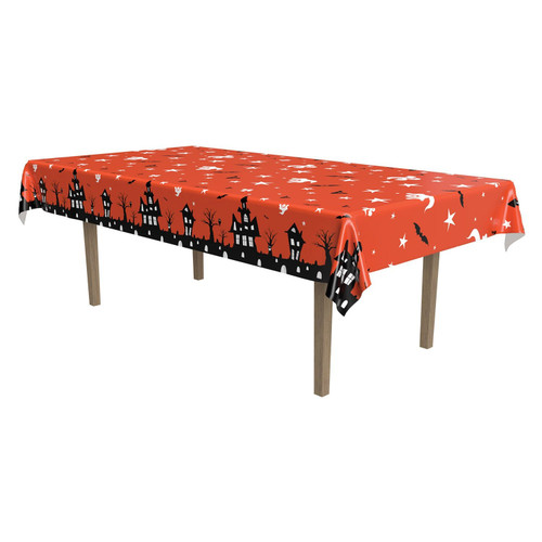 Haunted House Plastic Tablecover, perfect for Halloween parties and festive gatherings. The rectangular tablecover features a bright orange background decorated with a pattern of white ghosts, black bats, and scattered stars. Along the border, a repeating silhouette design showcases haunted houses, gravestones, and eerie trees. Measures 54in x 108in.
