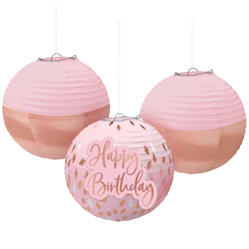 Blush Birthday Paper Lanterns. This set of paper lanterns features two with a two tone design of light pink and rose gold, and one that is light pink with rose gold confetti and a cardstock add on that says "Happy Birthday" in elegant script. Package includes 3 count decorations measuring 9.5in.