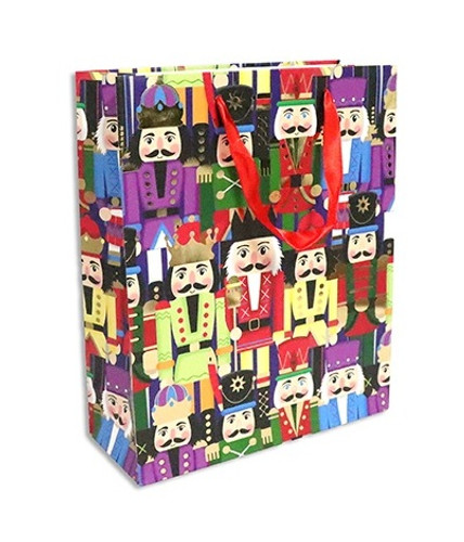 Nutcrackers Medium Gift Bag. This paper bag features a pattern of colorful nutcrackers on a dark blue background. It's accented with gold foil, and includes red ribbon handles and a matching gift tag. Measures 7in x 9in x 3.75in.