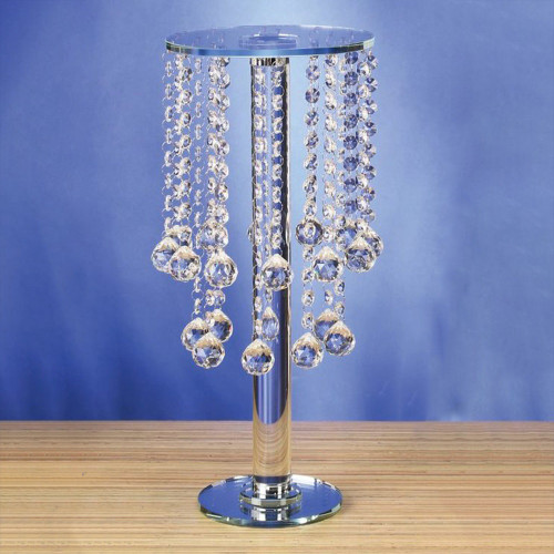 This Round Crystal Centerpiece Stand features a clear stand with a clear circular top, a smaller mirror circular base, and strands of clear crystals with larger tear drop shapes at the bottom. Measures 17.5in tall, 7.75in wide.