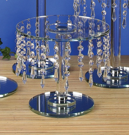 This Round Crystal Centerpiece Stand features a clear stand with a clear circular top, a smaller mirror circular base, and strands of clear crystals. Measures 13in tall, 9.75in wide.