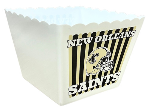 New Orleans Saints Plastic Popcorn Box. This white soft plastic box has a scalloped trim and a black and muted gold striped graphic printed on two of its four sides. The design features a gold football helmet between "NEW ORLEANS" above and "SANTS" below in white text. Package includes 1 count box measuring about 9in x 9in, 6.75in tall.