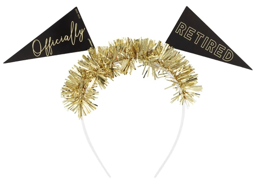 Officially Retired Fringe Headband. This white plastic headband is topped with gold foil fringe and two printed cardstock flag headboppers in black with matte gold text. One says "Officially" in script, the other "RETIRED" in outlined capital print. The undersides of the flags are white. One size fits most.