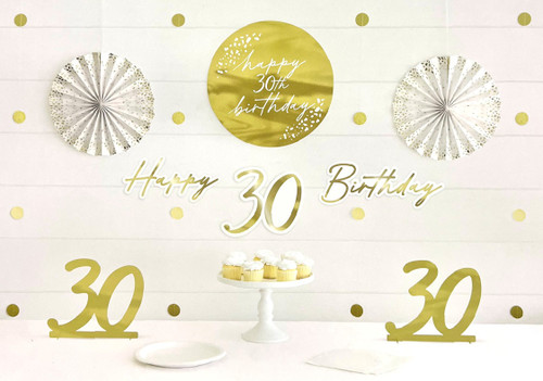Golden 30th Birthday Decoration Kit. With a color scheme of gold foil and white, and a pattern of animal spots, this set includes cardstock centerpieces, cutouts, and paper fans that feature "30." Package includes 2 count gold foil centerpieces measuring 8.5in, 4 count garlands of circle cutouts measuring 7.25ft, 2 count fan decorations measuring 12in, 4 count cutouts 14.5in, 8.75in, 11.25in x 5.5in, and 14.5in x 5.75in, as well as 25 count adhesive squares.
