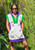 Adult Mardi Gras Tennis Dress. In purple and green with a white cover look, on the front it features sequin appliqués of crowns, king cakes, stars, masks, and a trumpet. Complete with a zipper and pockets for convenience.