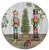 Vintage Nutcracker Charger. This plastic plate features a picture of two nutcrackers standing beside a Christmas Tree. One version is mostly red and green in front of a white wooden background. Desired style not guaranteed. Measures 13in.
