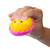 Mochi Squish Easter Chick Toy - yellow chick in pink shell being squished. Available in green chick in pink shell, yellow chick in pink shell, yellow chick in purple shell, or blue chick in white shell, this toy has a tiny printed expression of two eyes and a beak and is very squishy. Desired color not guaranteed. Package includes 1 count toy measuring 2in.