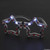 Red White & Blue Light Up Star Glasses in the dark. These plastic star shaped frames have a red, white, and navy blue star pattern, and have white lights along the top that activate with a button. Batteries included but not replaceable. Package includes 2 pairs of glasses. Measures 6in. One size fits most.