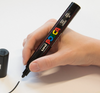 Hand using POSCA PC-5M marker to draw clean lines on a smooth white surface