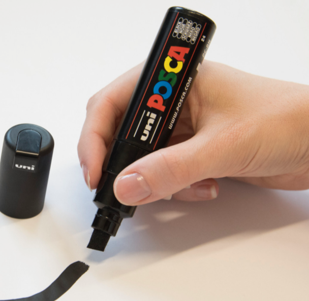 Artist using a POSCA PC-8K chisel tip paint marker to draw on a smooth white surface