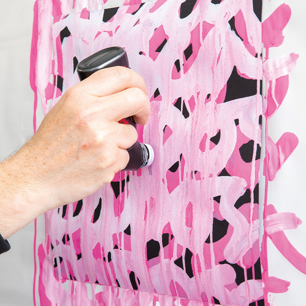 Artist applying POSCA MOP’R marker to a pink patterned fabric surface using drip technique