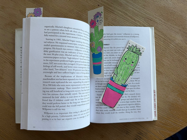 POSCA Cactus Colour-In Bookmarks on open book featuring potted cactus illustrations in pastel green and pink