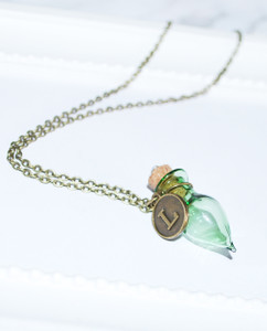 Lagom Bottle Necklace Green-Bronze side view on grey scalloped background Lagom Bottle Necklace Green-Bronze side view on grey scalloped background