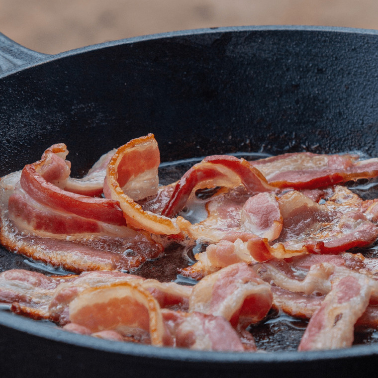 Thick Cut Smoked Bacon Frying in a Pan