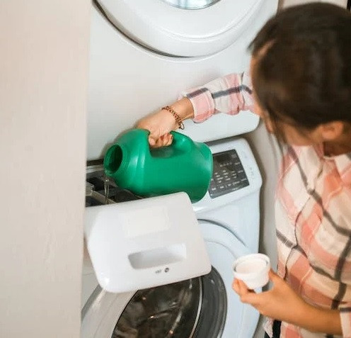 Blank cotton sweatshirt beside a washing machine for a practical clothing care guide
