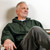 Just Sweatshirts Hooded Pullover Park Green 100% Cotton dark green hoody on a man sitting comfortably relaxed.