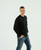 Just Sweatshirts Men's long sleeve 100% cotton T-shirt in Black, worn by a young man with hands in pockets.