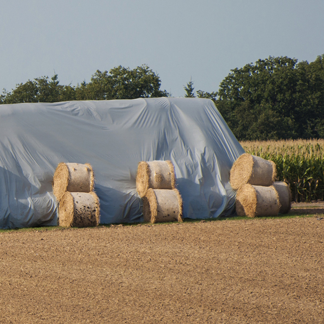 Large 45'x54' reflective dual-fabric hay tarp protecting the bales of hay underneath.