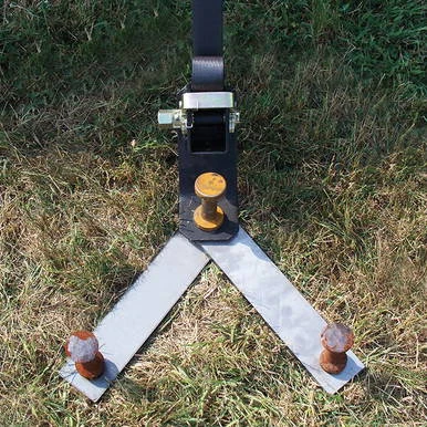 24'' Stake Plate, metal construction with orange and rusty stakes on grassy ground for marking or safe area delineation.