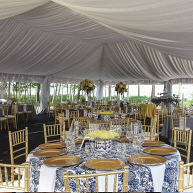 Celina Tent Frame Tent Liner 40' x 20' Mid, interior view of a decorated event tent with elegant table settings, gold chairs, and floral centerpieces under the tent's draped fabric ceiling.