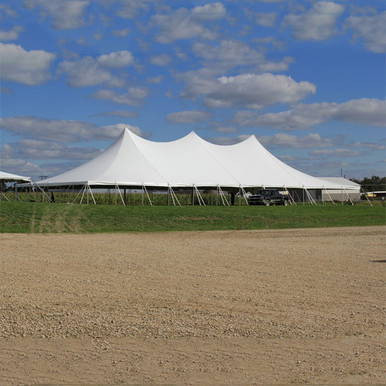 Celina Tent 60' x 120' Premiere II Series High Peak Pole Tent, Sectional Tent Top, Complete, large white event tent with a peaked roof set up outdoors on grassy field under a blue sky with clouds.