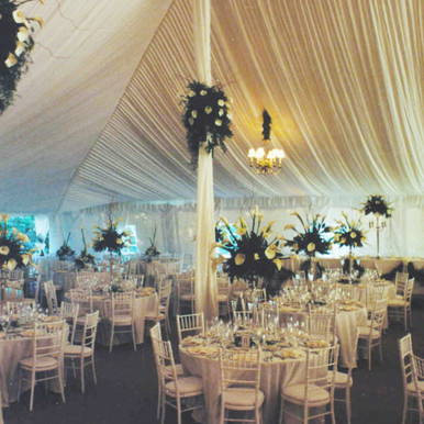 Center Pole Drape - 21' , elegant event tent interior with tall draped fabric and floral centerpieces.