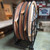 Celina Tent 60-inch Round Wood Table, folded and stored in a metal stand for easy transportation and space-saving storage.
