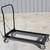 Heavy Duty Chair Cart, a black metal platform cart with four caster wheels and a handle for easy transportation of chairs.