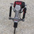 Side Handle Rhino Gas Driver, outdoor equipment with a side handle and gas-powered motor for driving nails or fasteners.