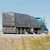 20' x 27' Lumber Tarp, 1 Flap, covering cargo on a flatbed truck while parked on a highway under clear blue skies.