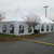 7' x 20' Cathedral Window Sidewall, large white tent with arched windows, set up outdoors in a parking lot with a tree and streetlamp nearby.