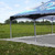 25' x 25' Polyester Drop Cloth, outdoor scene with a large, gray drop cloth underneath a blue canopy tent on a grassy field.