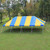 Celina Tent 20' x 40' Classic Series Pole Tent, 1 Piece Tent Top, Complete, set up outdoors on grass with trees in the background, featuring a vibrant yellow and blue striped canopy for outdoor events.