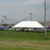 Celina Tent 20\' x 40\' Classic Series Pole Tent, 1 Piece Tent Top, Complete, outdoor event tent with white canopy set up on grassy area with parking lot and carnival rides in the background.