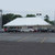 Celina Tent 20' x 40' Classic Series Pole Tent, 1 Piece Tent Top, Complete, large white event tent set up in an outdoor parking lot with multiple cars and trees in the background.