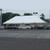 Celina Tent 20' x 40' Classic Series Pole Tent, 1 Piece Tent Top, Complete, outdoor event tent set up in a parking lot with cars and trees in the background.