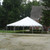 Celina Tent 30' x 30' Classic Series Pole Tent, 1 Piece Tent Top, Complete, outdoor event tent set up on grass in a residential area with trees and house in the background.