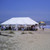 Celina Tent 20' x 40' Classic Series Pole Tent, Sectional Tent Top, Complete, large white event tent set up on the beach with people and tables underneath on a sunny day.