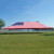 Celina Tent 30' x 60' Classic Series Pole Tent, Sectional Tent Top, Complete, large outdoor event tent with American flag pattern on the top, set up on a grassy field under a clear blue sky.
