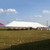 Celina Tent 40' x 100' Classic Series Pole Tent, Sectional Tent Top, Complete, outdoor event tent set up on a grassy field under a blue sky with scattered clouds.