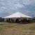 Celina Tent 40' x 40' Classic Series Pole Tent, Sectional Tent Top, Complete, outdoor event tent with people seated beneath, set up on grassy area with cloudy sky in background.